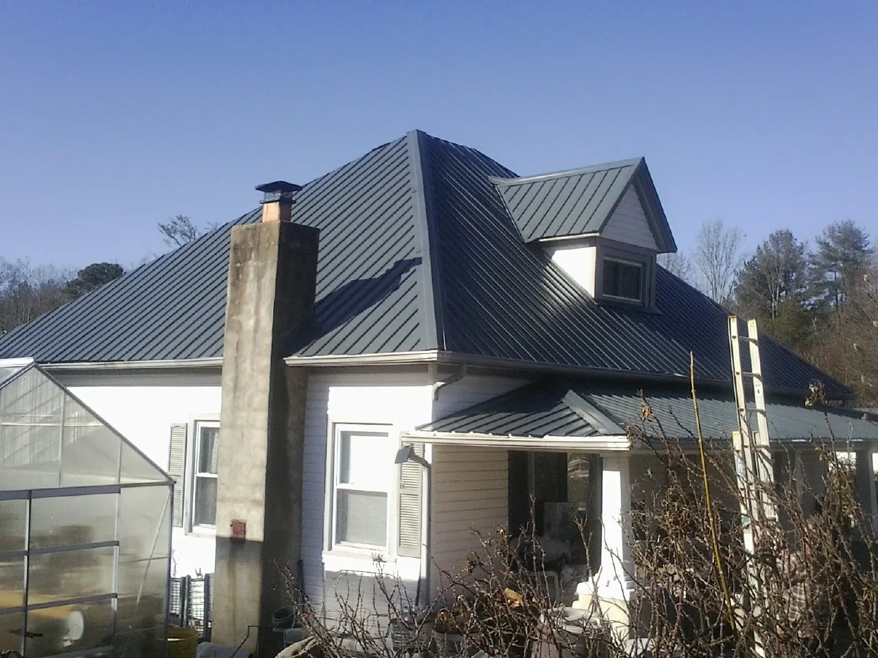 Dark blue standing seam metal roof on a white farmhouse with dormer — Slate & Tile Roof Repair by Roofing Brothers in Beaver Springs