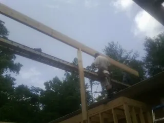 Carpenter setting a ridge beam over a new addition frame — Ice Dam Removal by Roofing Brothers in Beaver Springs