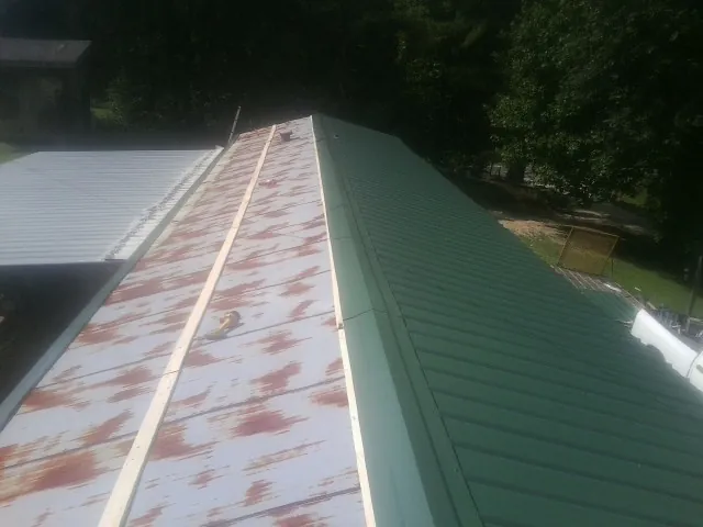 Old rusted panels beside newly installed green metal roofing — Wind Damage Roof Repair by Roofing Brothers in Beaver Springs