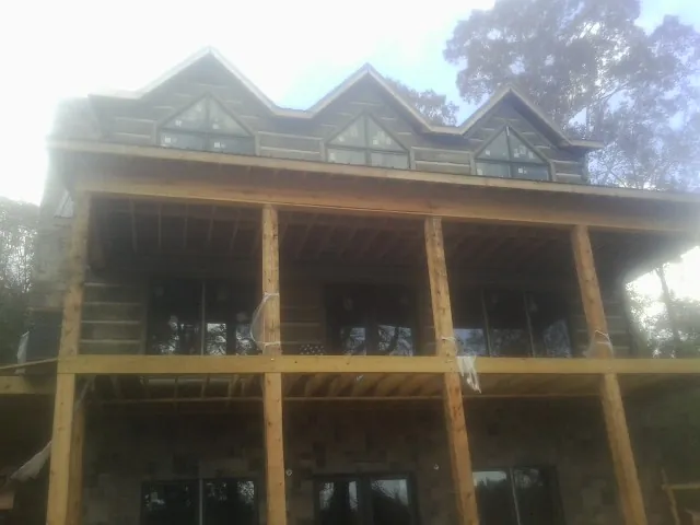 Dormers and porch framing on a large log home under construction — Roof Coating work by our crew in Beaver Springs