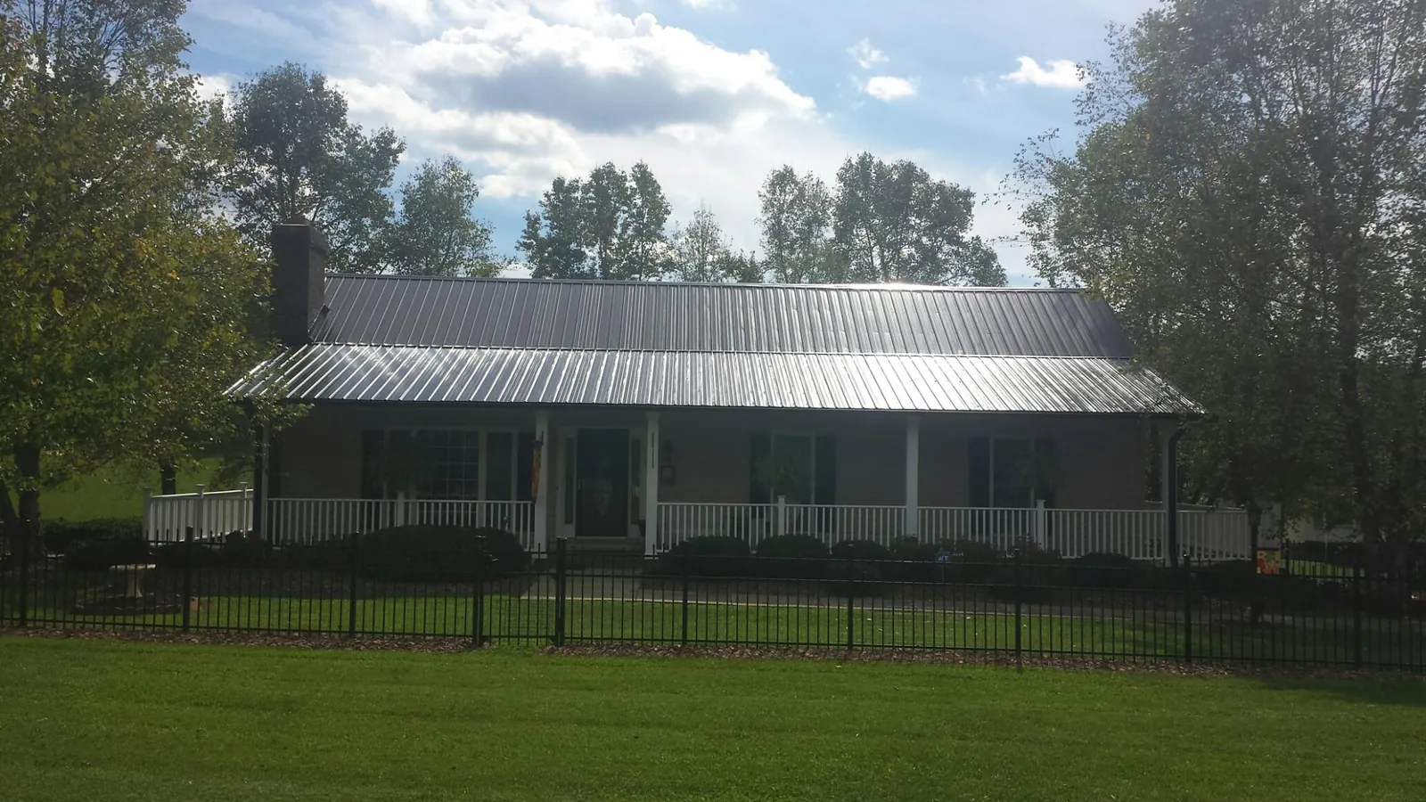 Gray metal roof on a brick ranch with a full width front porch — Gutter Guard Installation work by our crew in Beaver Springs