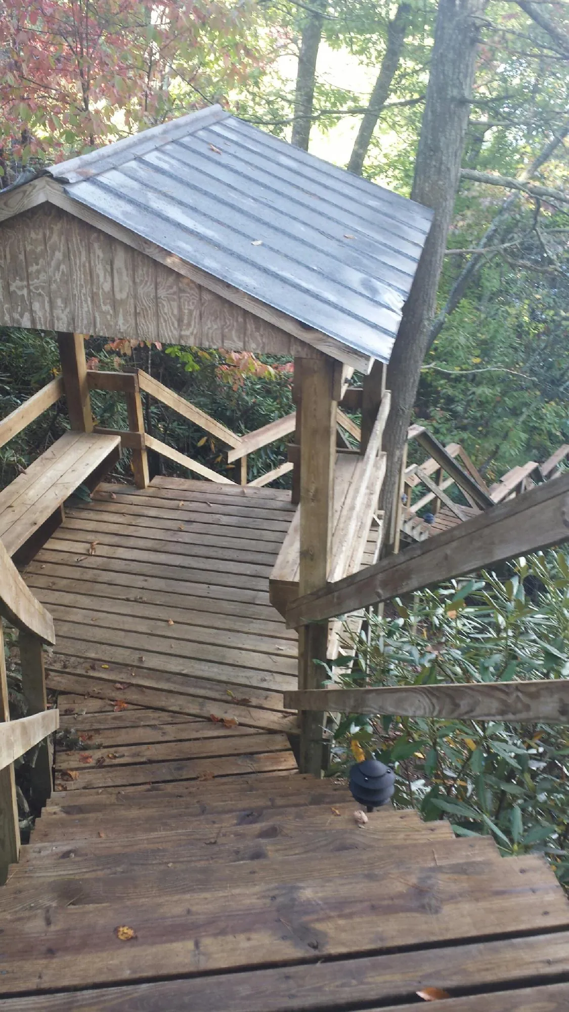 Metal roofed shelter over wooden steps on a wooded walkway — Skylight Repair & Installation work by our crew in Beaver Springs