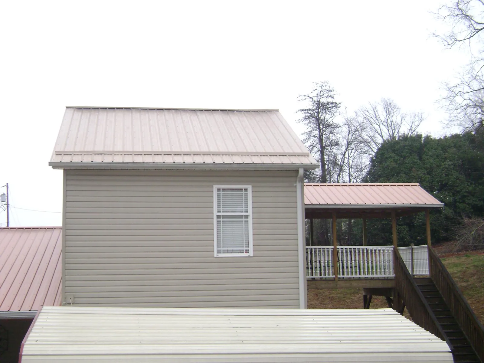 Tan metal roofs on a two story addition and attached porch, from a Roof Replacement job in Beaver Springs