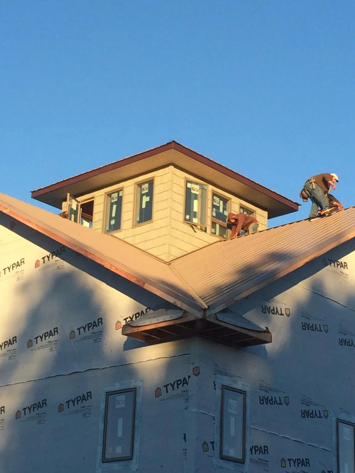 Roofers working around a rooftop cupola on a new metal roof at sunset — Roof Waterproofing in Beaver Springs by Roofing Brothers